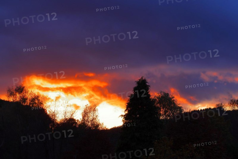 Sunset with dramitic dark clouds, sun shining through a gap in the clouds, red sky, burning sky, silhouette, Rothaargebirge, North Rhine-Westphalia, Germany, Europe