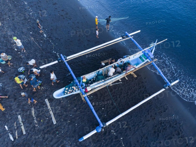 Fishermen unload their catch from their outrigger boat in the morning. Amed, Karangasem, Bali, Indonesia, Asia