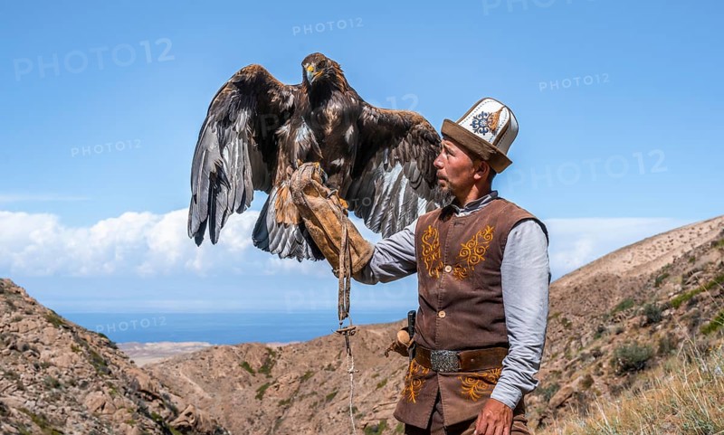 Traditional Kyrgyz eagle hunter with eagle in the mountains, hunting, eagle spreads its wings, near Bokonbayevo, Issyk Kul region, Kyrgyzstan, Asia