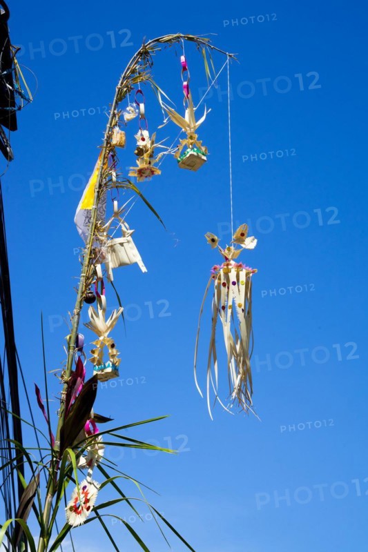 Ornate jewellery woven from palm leaves on bamboo poles, on a village street in Amed, Karangasem, north-east Bali, Indonesia, Asia