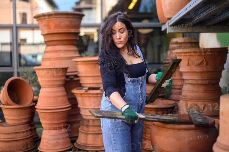A woman examines a terracotta pot in a pottery workshop