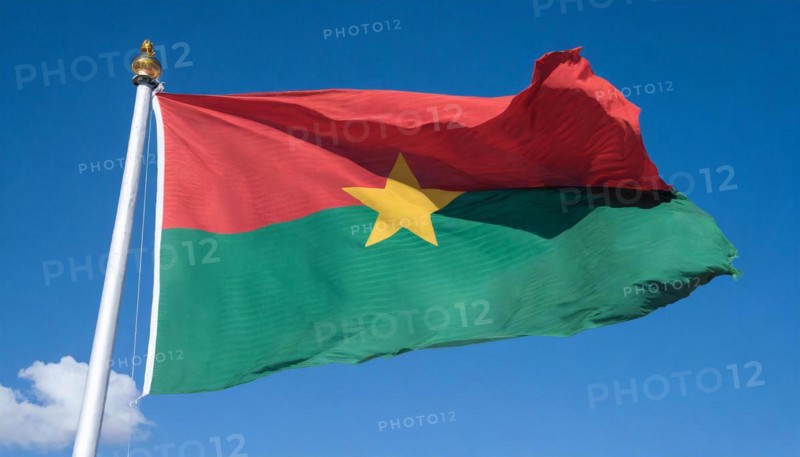 The flag of Burkina Faso flutters in the wind, isolated against the blue sky