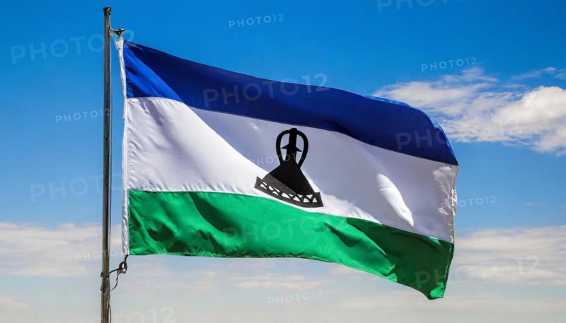 The flag of Lesotho, fluttering in the wind, isolated, against the blue sky