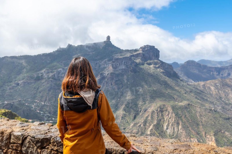 A tourist woman looking at Roque Nublo from a viewpoint on the mountain. Gran Canaria, Spain, Europe
