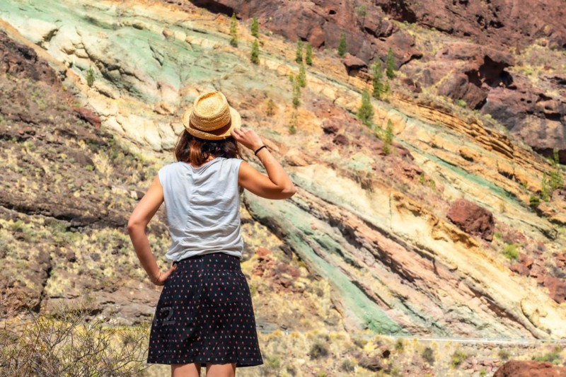 A tourist woman at the Natural Monument Azulejos de Veneguera or Rainbow Rocks in Mogan, Gran Canaria