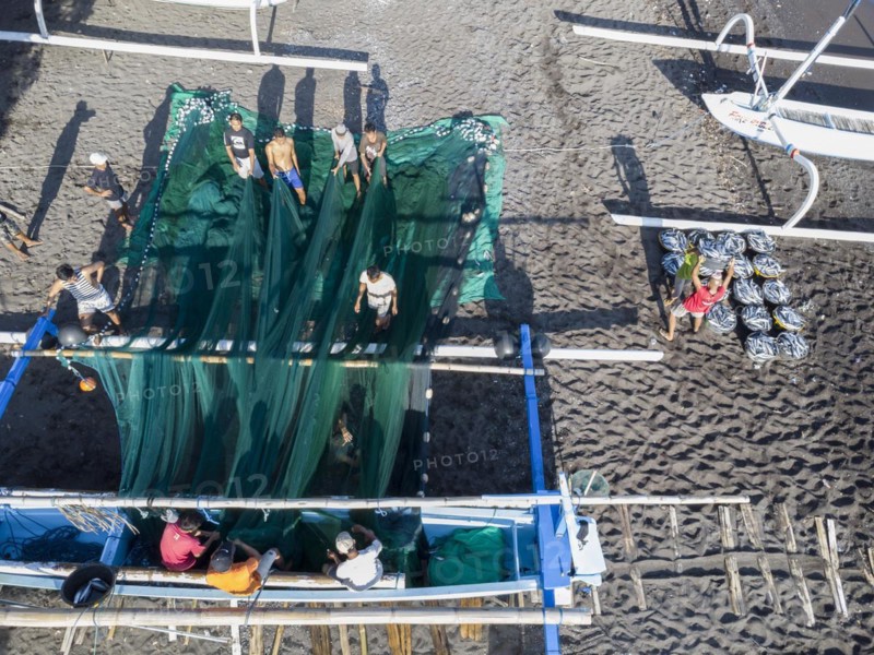 Fishermen unload their catch from their outrigger boat in the morning. Amed, Karangasem, Bali, Indonesia, Asia