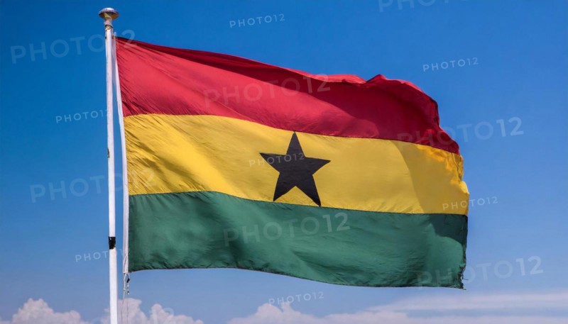 The flag of Ghana flutters in the wind, isolated against a blue sky