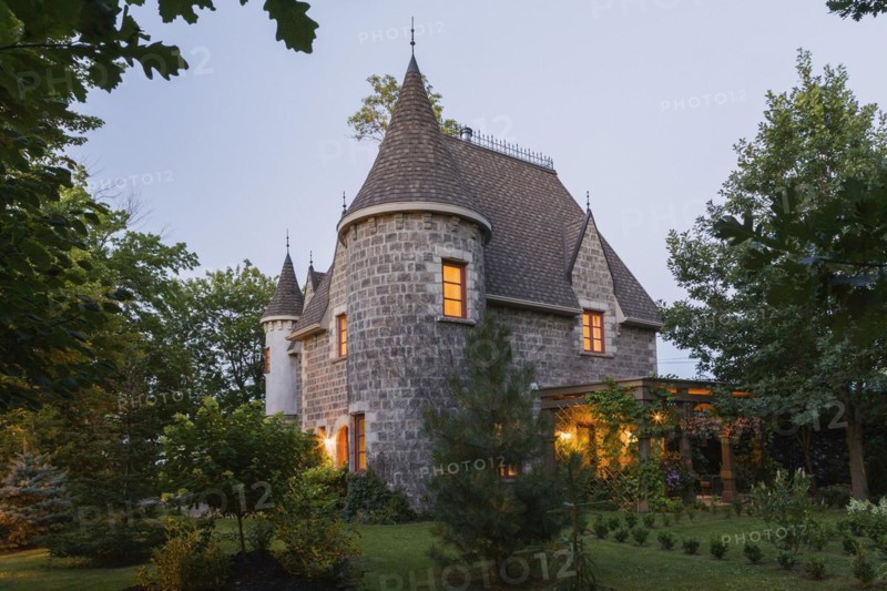 2006 reproduction of a 16th century grey stone and mortar Renaissance castle style residential home facade at dusk in summer, Quebec, Canada, North America