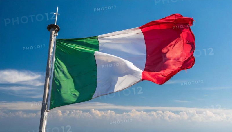 The flag of Italy flutters in the wind, isolated against a blue sky