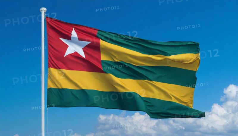 The flag of Togo flutters in the wind, isolated against a blue sky