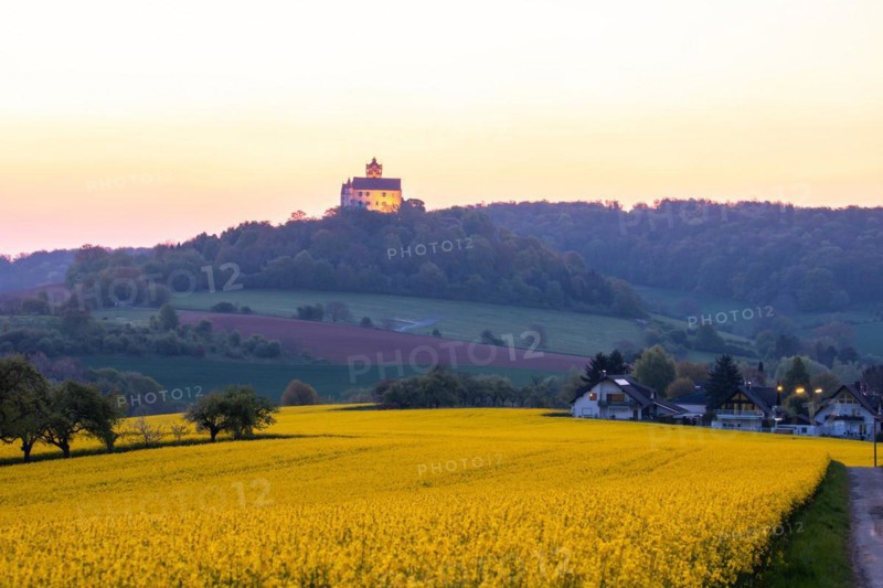 Landscape at sunrise. Beautiful morning landscape with fresh yellow rape fields in spring. Small castle in the yellow fields on a hill. Historic Ronneburg Castle in the middle of nature, Ronneburg, Hesse, Germany, Europe