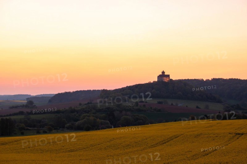 Landscape at sunrise. Beautiful morning landscape with fresh yellow rape fields in spring. Small castle in the yellow fields on a hill. Historic Ronneburg Castle in the middle of nature, Ronneburg, Hesse, Germany, Europe