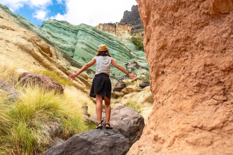 A tourist woman enjoying the natural monument at the Azulejos de Veneguera or Rainbow Rocks in Mogan, Gran Canaria