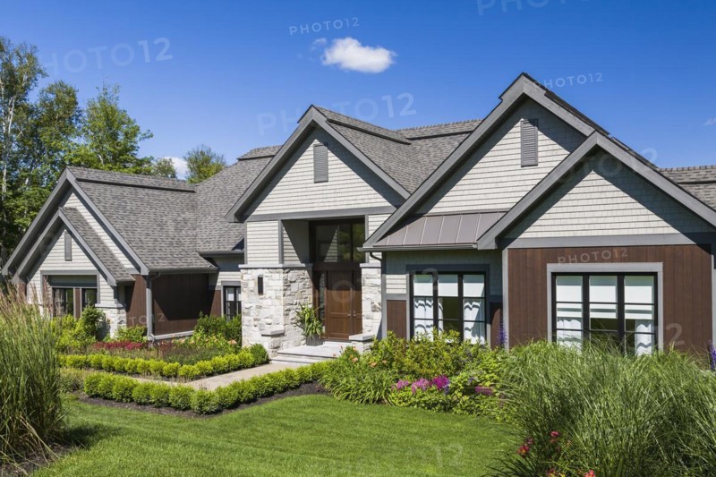 Contemporary natural stone and brown stained wood and cedar shingles clad luxurious bungalow style home facade in summer, Quebec, Canada, North America