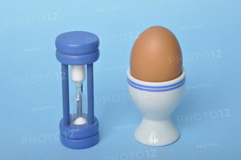 Boiled egg and hourglass on a blue background