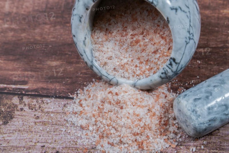 Himalayan pink salt in a ceramic mortar on a wooden table with a copy space