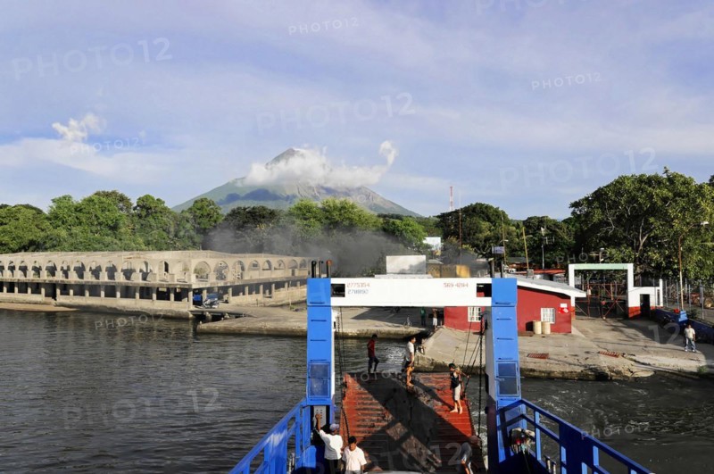 Lake Nicaragua, Ferry on the shore of a lake with an active volcano in the background and cloudy sky, Nicaragua, Central America, Central America