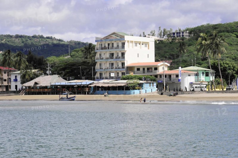 San Juan del Sur, Nicaragua, A view of the shore with a multi-storey building next to palm trees and beach, Central America, Central America