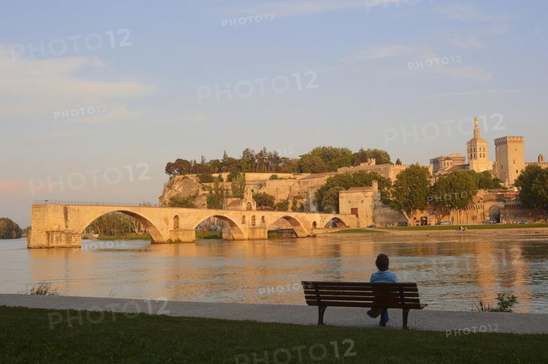 Woman on a park bench on the banks of the Rhone, Pont Saint Benezet bridge, Papal Palace and Notre-Dame des Doms Cathedral, Avignon, Vaucluse, Provence-Alpes-Cote d'Azur, South of France, France, Europe