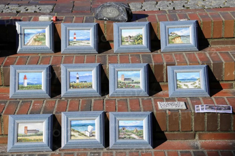 Westerland, Sylt, Schleswig-Holstein, Germany, Europe, Several framed paintings of lighthouses and beach scenes displayed on a tiled floor, North Frisian Island, Schleswig Holstein, Europe