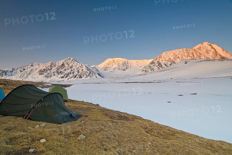 Icy tents in expedition camp at sunrise over the mountain peaks in the snow-covered Tavan Bogd National Park, Mongolian Altai Mountains, Western Mongolia, Mongolia, Asia