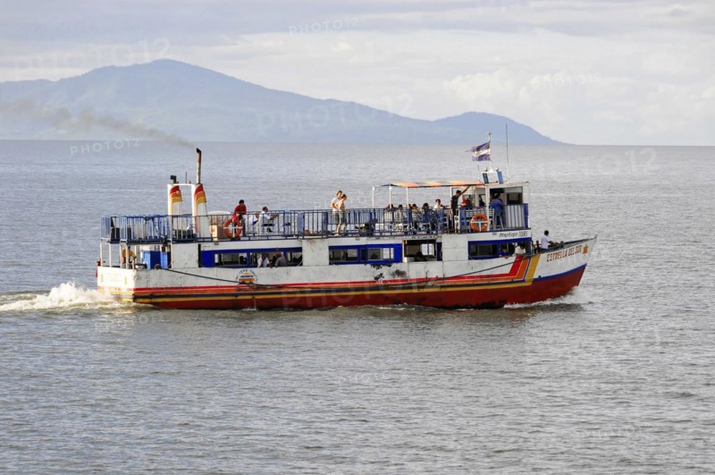 Lake Nicaragua, behind the island of Ometepe, ferry with passengers on the open sea, waving flag and a cloudy sky in the background, Nicaragua, Central America, Central America