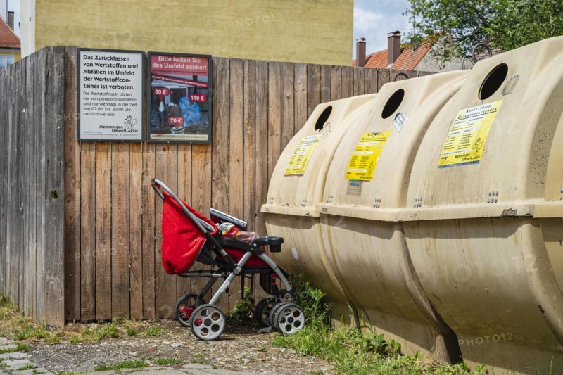 Pushchair left in front of a recycling container in the old town centre of Memmingen, Swabia, Bavaria, Germany, Europe