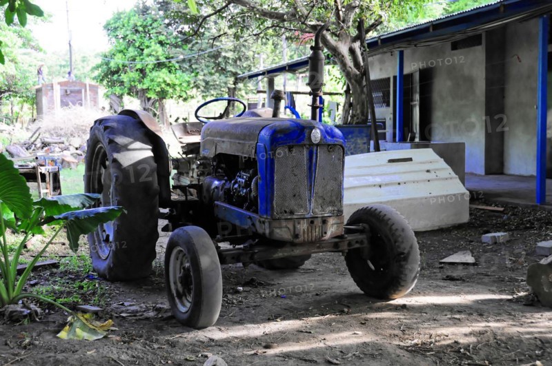 Ometepe Island, Nicaragua, An old, blue tractor stands in front of rural buildings, Central America, Central America