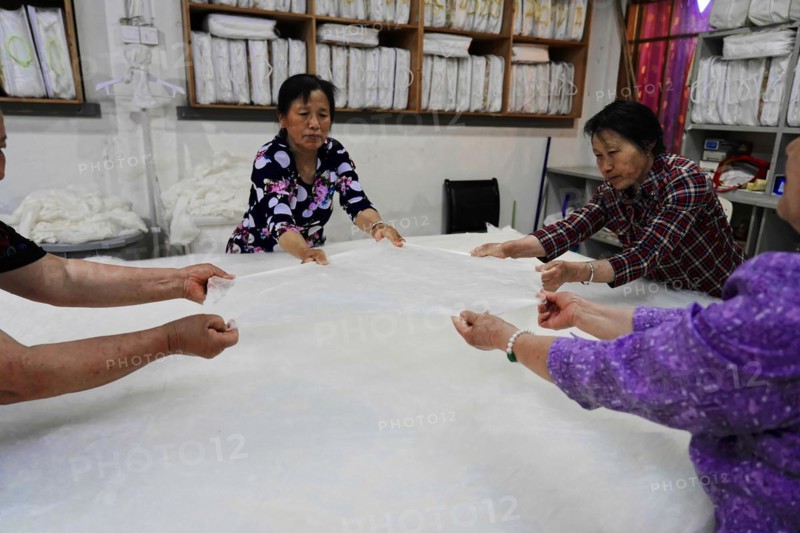 Silk factory Shanghai, Several workers stretching a large length of fabric together, Shanghai, China, Asia