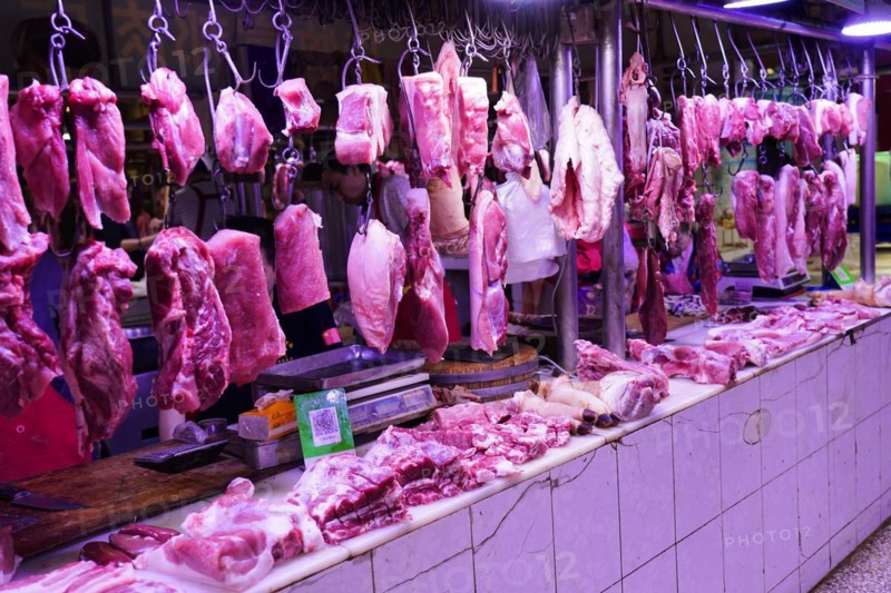 Chongqing, Chongqing Province, China, Pieces of meat hanging on hooks in an internally lit market stall, Chongqing, Chongqing Province, China, Asia