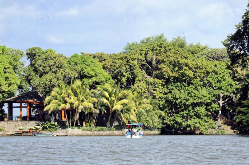 Granada, Nicaragua, View of Lake Nicaragua with a small boat surrounded by palm trees and a pavilion on the shore, Central America, Central America