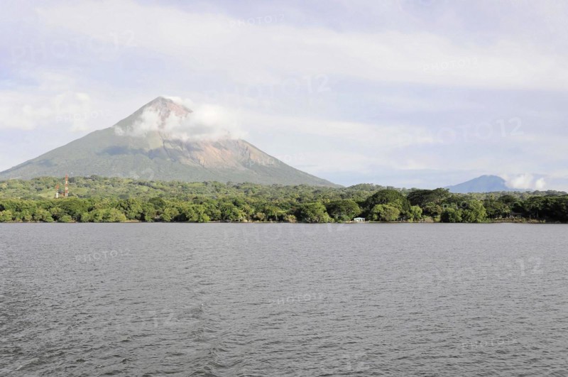 Lake Nicaragua, Ometepe Island in the background, Calm lake with a view of a smoking volcano, surrounded by green vegetation and a cloudy sky, Nicaragua, Central America, Central America