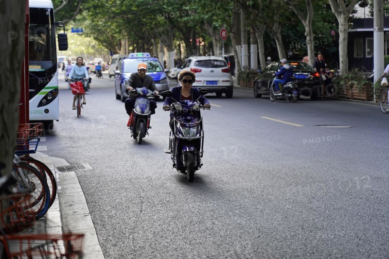 Traffic in Shanghai, Shanghai Shi, people riding scooters and bicycles along a tree-lined street, Shanghai, People's Republic of China