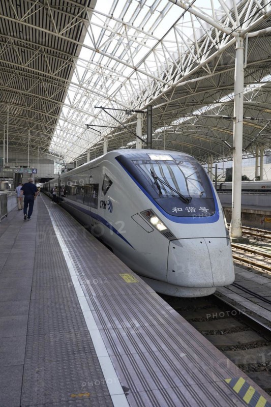 Fast trains, CRH on the platform, Hongqiao railway station, Shanghai, China, Asia. Travellers walk along a train on a platform in a large station concourse, Yichang, Hubei Province, Asia