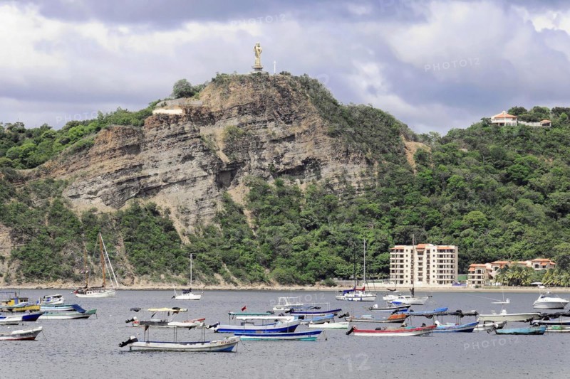 San Juan del Sur, Nicaragua, A statue of Jesus is enthroned on a wooded hill above a bay with boats, Central America, Central America