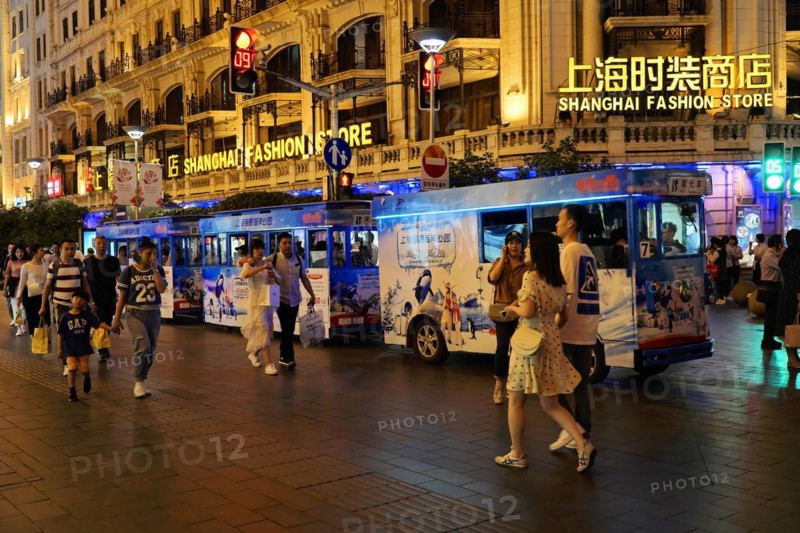 Evening stroll through Shanghai to the sights, Shanghai, Lively shopping street at night with a brightly lit bus and passers-by, Shanghai, People's Republic of China