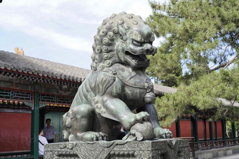 New Summer Palace, Beijing, China, Asia, Statue of a Chinese stone lion in front of traditional architecture and blue sky, Beijing, Asia