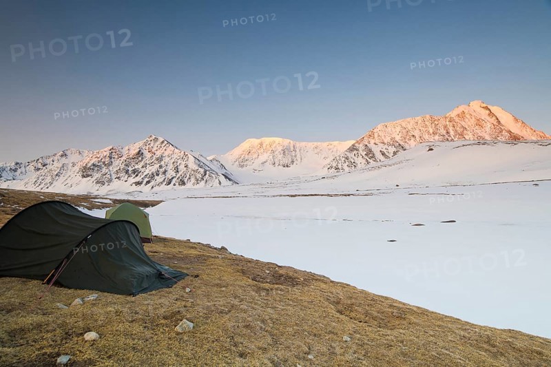 Icy tents in expedition camp at sunrise over the mountain peaks in the snow-covered Tavan Bogd National Park, Mongolian Altai Mountains, Western Mongolia, Mongolia, Asia