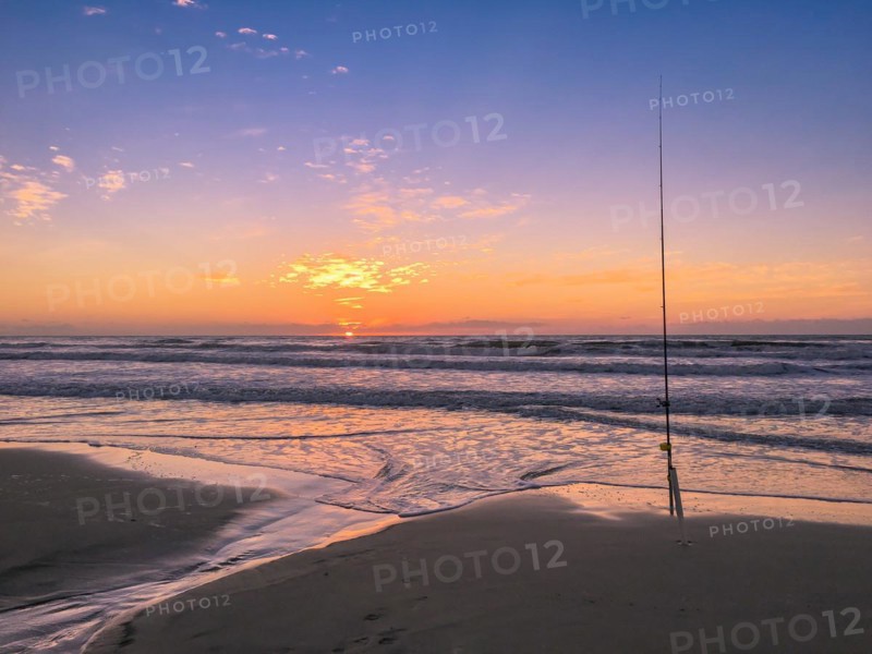 Fishing rod on beach at sunset, surfing cast