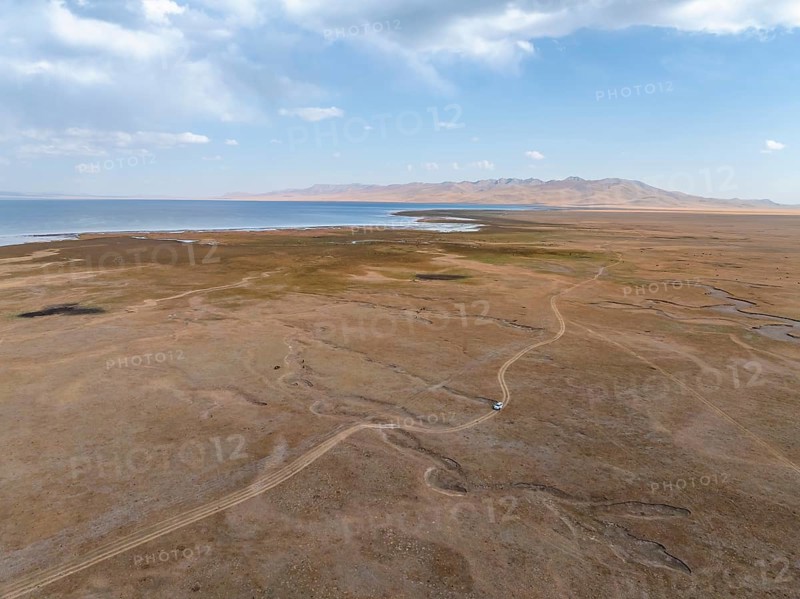 Road and off-road vehicle, Aerial view, Vast empty landscape at the mountain lake Song Kul in autumn, Moldo Too Mountains, Naryn region, Kyrgyzstan, Asia