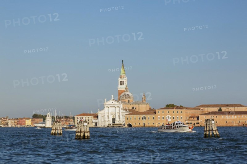 Canal lane markers in Venetian lagoon and 16th century Benedictine church of San Giorgio Maggiore on San Giorgio Maggiore Island, Venice, Veneto, Italy, Europe