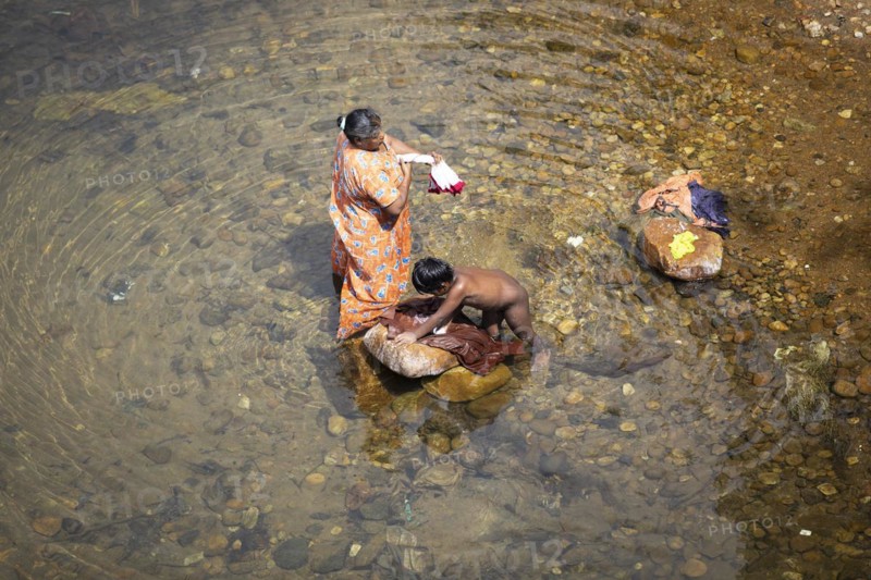 Indian woman and her son washing clothes in the Periyar River, Mundakayam, Kerala, India, Asia