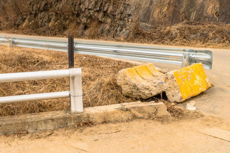 End buttress of street curb broken off and laying on ground at intersection in countryside in South Korea