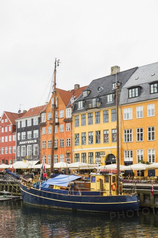 Colourful 17th century apartment buildings and houses with moored blue and yellow sailboat along the Nyhavn canal, Copenhagen, Denmark, Europe