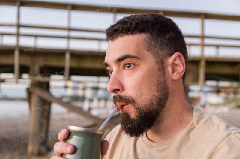 Man drinking chimarrao, mate tea tea (an infusion of yerba mate tea tea with hot water) at sunset in uruguay