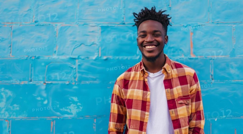 Black young positive man with dreadlocks is smiling and standing in front of the building wall. Concept of confidence and positivity, AI generated