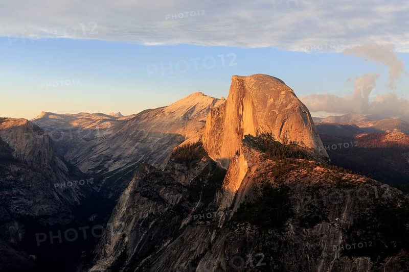 The setting sun bathes Half Dome in orange hues, surrounded by dramatic clouds, Yosemite National Park, North America, USA, South-West, California, California, North America