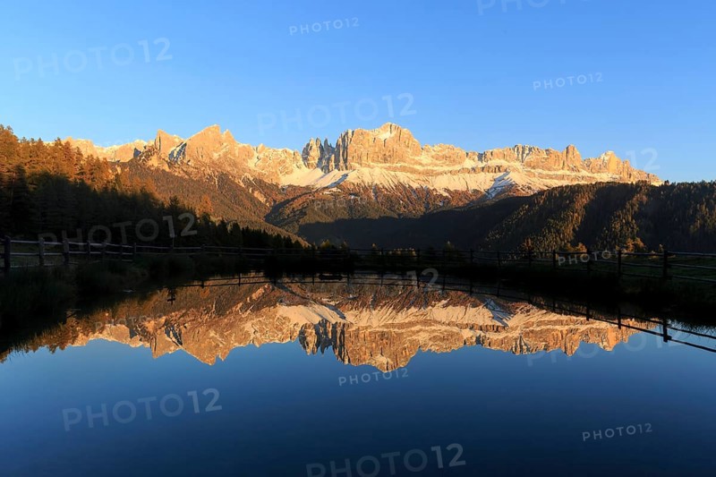 The last rays of the day illuminate the mountains reflected in a calm lake, Trentino-Alto Adige, Alto Adige, Bolzano province, Dolomites, Reflection rose garden at Wuhnleger Lake, San Cipriano