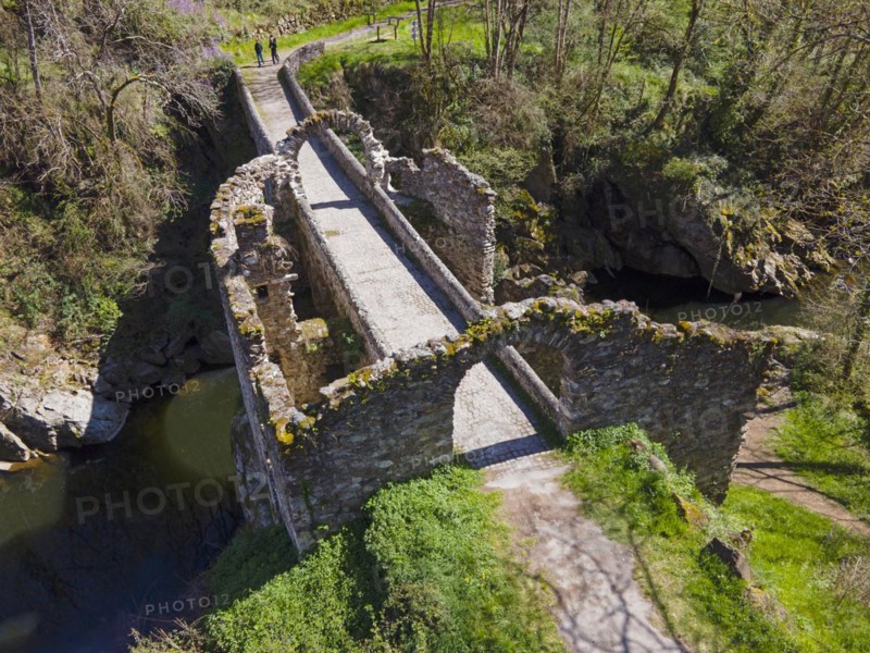 Ruins of a historic bridge with moss-covered stones over a river in a green landscape, Bridge of the Devil, Pont de Diable, Romanesque stone bridge, Ariege river, Montoulieu, Ariege, France, Europe