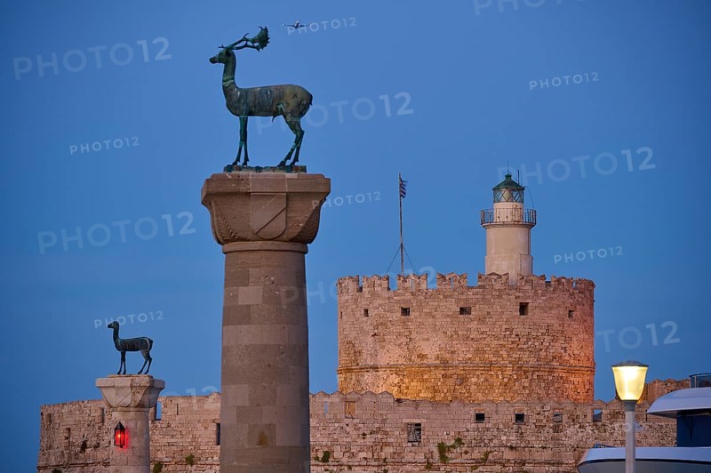 Bronze deer on pedestal in the foreground with old fortress walls and lighthouse in the background, Deer statue, Deer statue, Fort Agios Nikolaos, Mandraki harbour, European roe deer, Rhodes, Dodecanese, Greek Islands, Greece, Europe